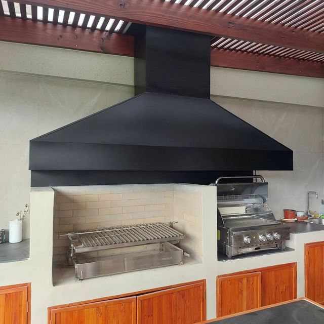 Campana básica negra sobre parrilla empotrada y muebles de madera