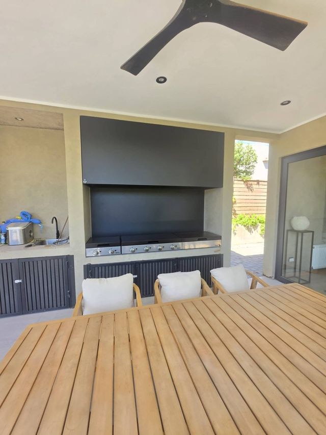 Quincho de Chicureo con mesa de madera y campana negra sobre las parrillas