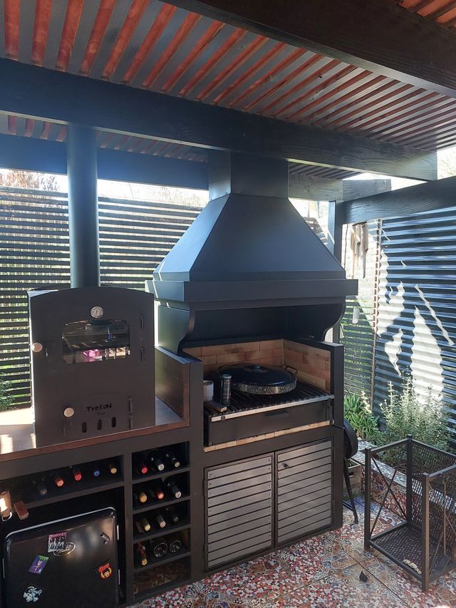 Campana con cinturón junto a horno y mueble de vinos bajo pérgola