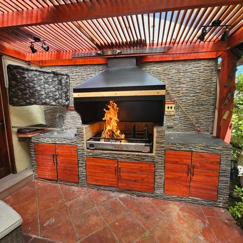 Quincho con campana de encaje de madera, fuego encendido y muebles de madera