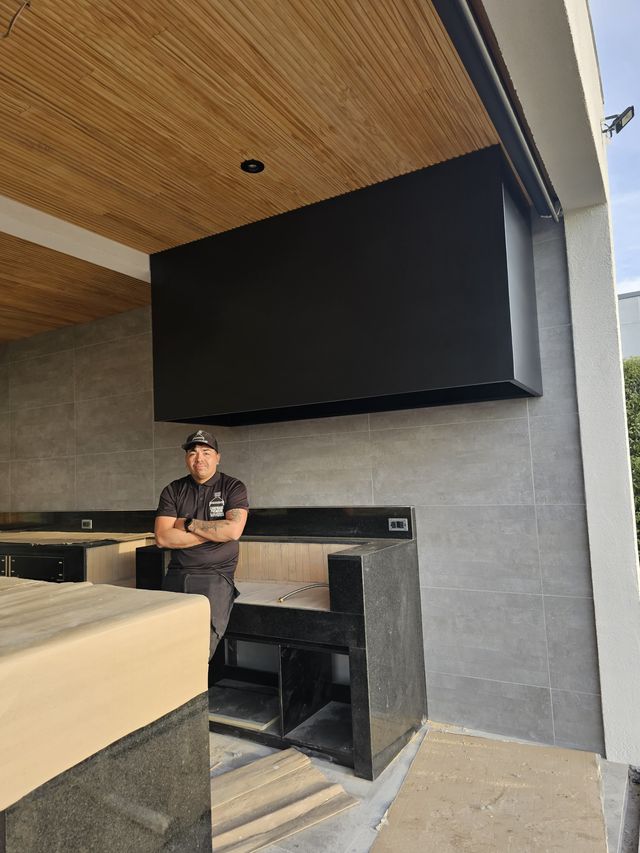 Instalador junto a una campana rectangular colgante bajo techo de madera