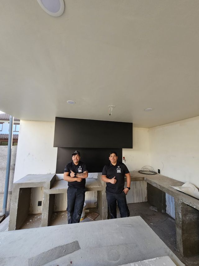 Dos instaladores frente a una campana rectangular sobre mesón de hormigón