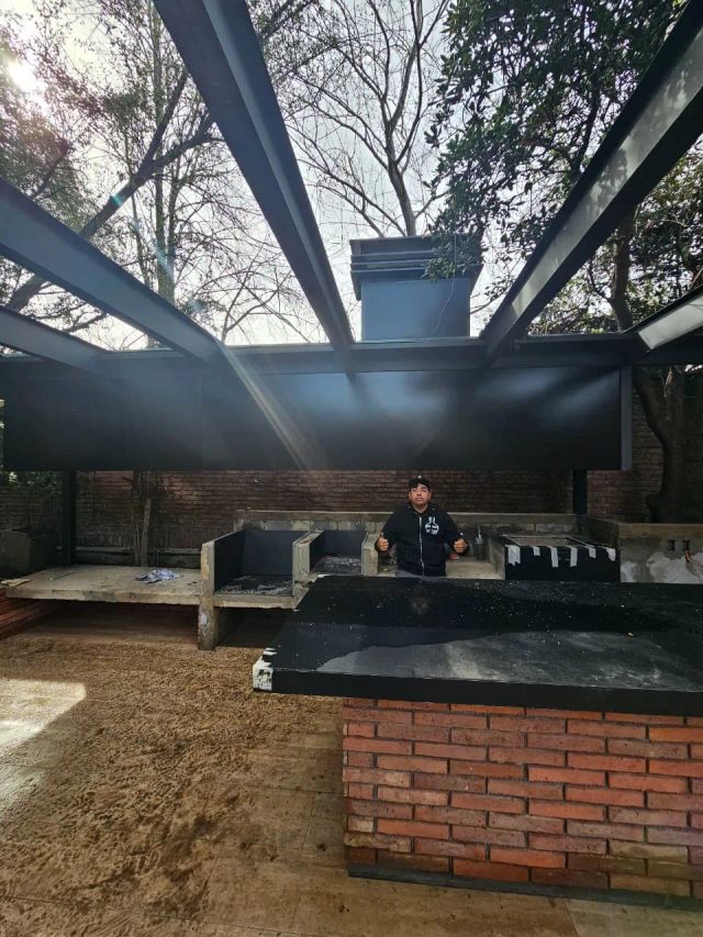 Quincho en obra bajo vigas metálicas, con instalador junto a la campana