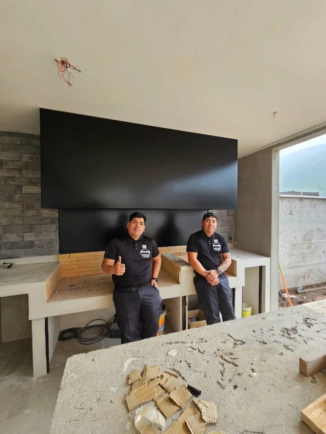 Dos instaladores bajo una campana negra con muro de piedra