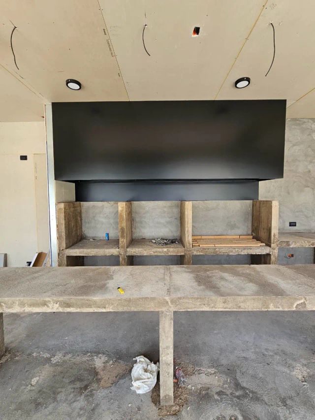 Campana negra rectangular instalada sobre fogón en obra gruesa