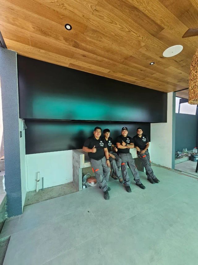 Equipo de instalación bajo una campana negra recién instalada, con cielo de madera