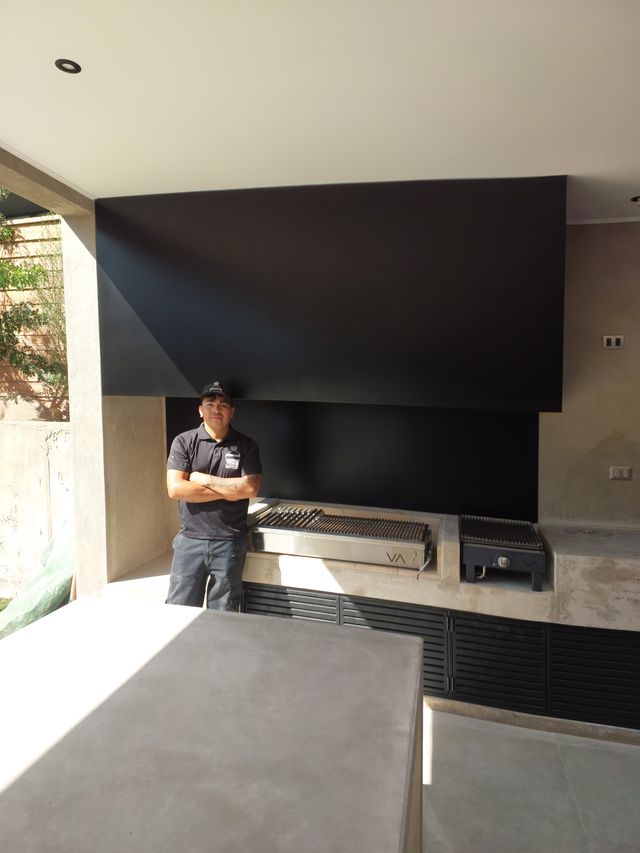 Instalador bajo una campana rectangular negra, con parrilla empotrada