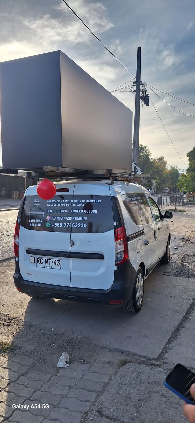 Camioneta rotulada de Campanas Premium con una campana sobre el techo
