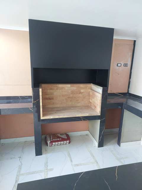 Fogón de ladrillo terminado bajo una campana rectangular negra