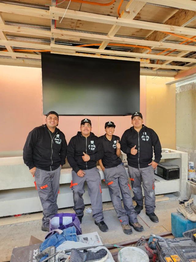 Equipo de instalación frente a una campana negra en obra