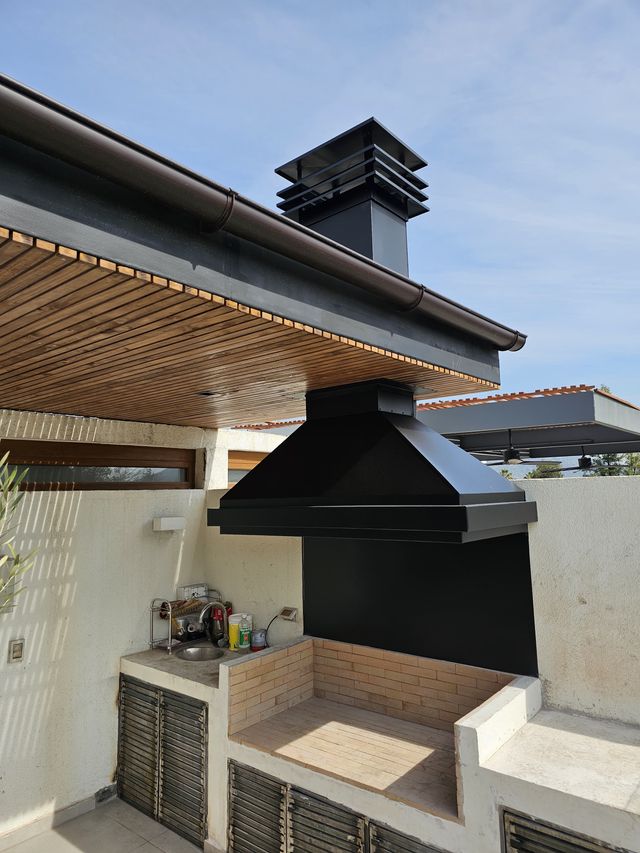 Campana piramidal con chimenea en un quincho exterior techado