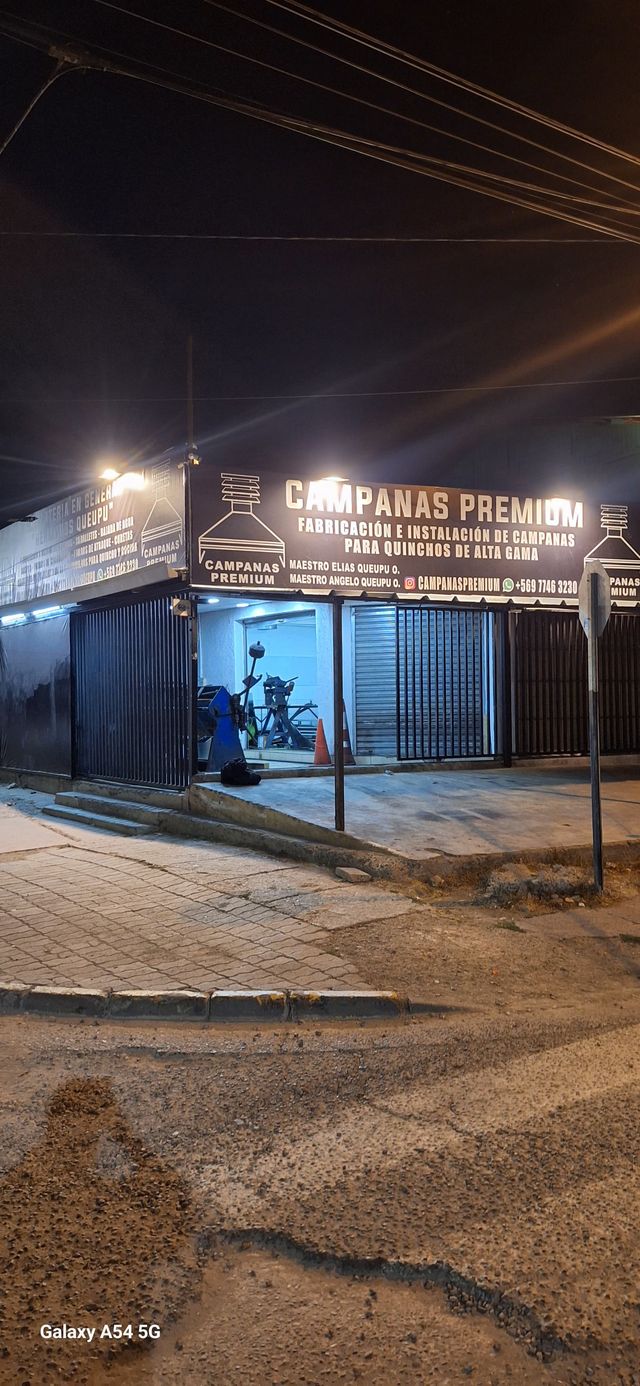 Fachada iluminada del taller de Campanas Premium, de noche