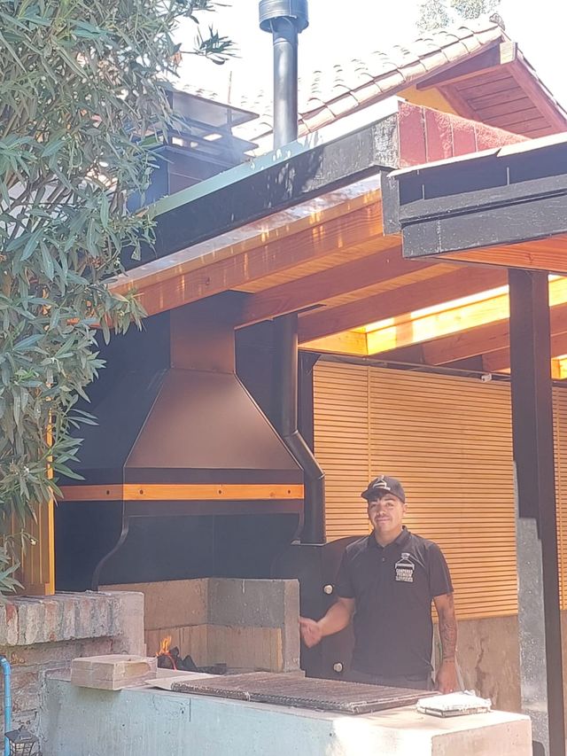 Instalador junto a una campana piramidal en un quincho con pérgola