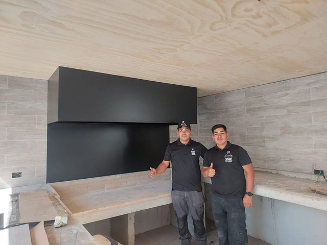 Dos instaladores frente a una campana rectangular de gran formato