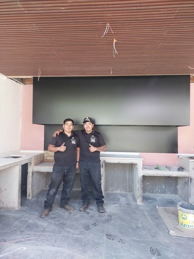 Dos instaladores bajo una campana rectangular sobre base de hormigón