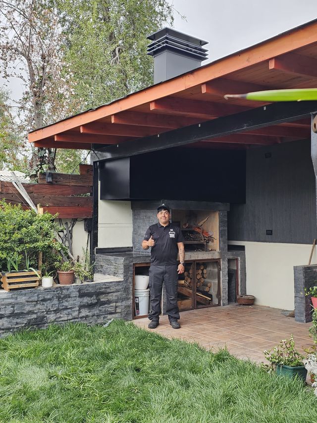Instalador frente a un quincho exterior con pérgola de madera y muro de piedra