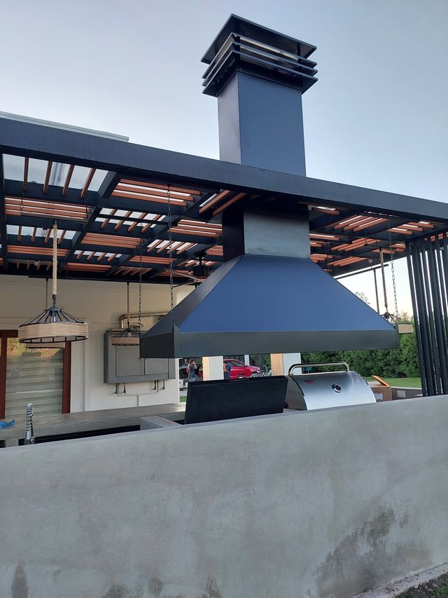 Campana piramidal con chimenea bajo una pérgola metálica