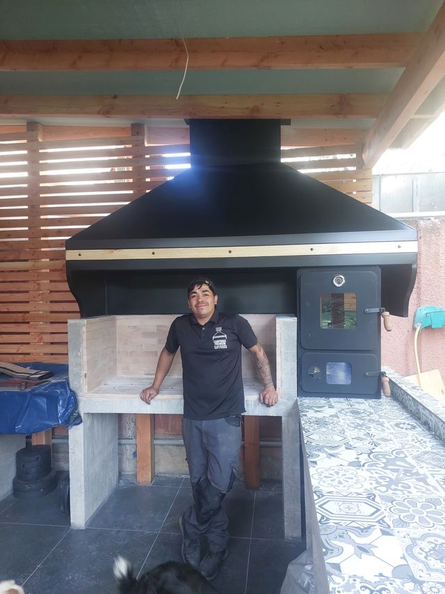 Instalador junto a una campana piramidal sobre fogón de ladrillo