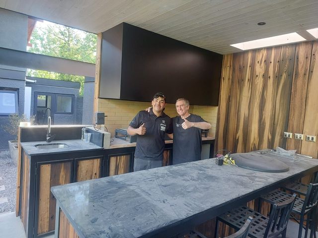 Dos integrantes del equipo bajo una campana rectangular sobre cocina de madera