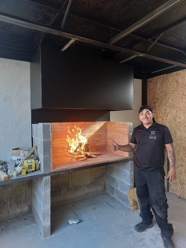 Instalador junto a una campana negra con el fogón encendido