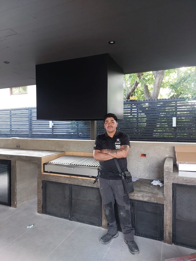 Instalador junto a una campana rectangular sobre la parrilla