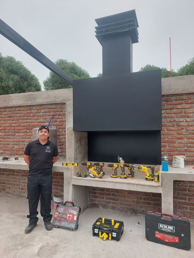 Instalador junto a una campana con chimenea sobre muro de ladrillo