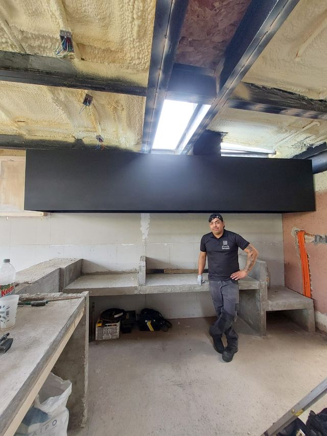 Instalador junto a una campana rectangular baja en un quincho en obra