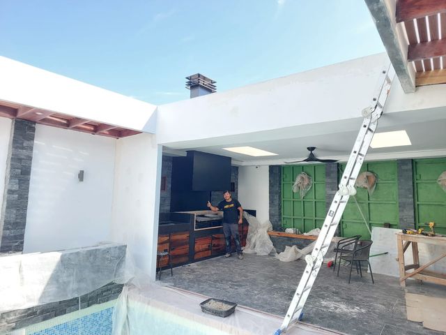 Quincho junto a la piscina, con un instalador al fondo