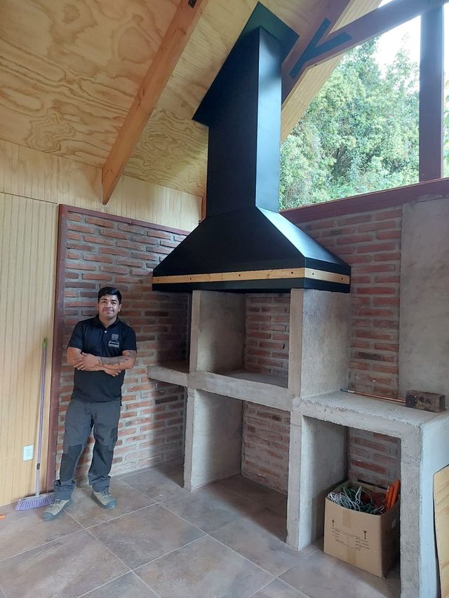 Instalador bajo una campana piramidal sobre fogón de ladrillo