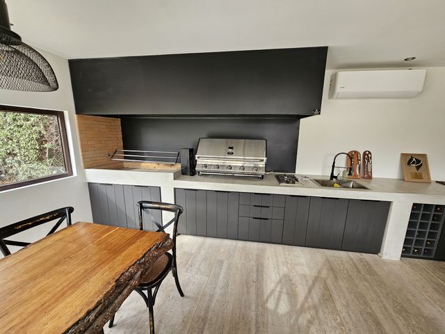Campana rectangular negra sobre cocina exterior con parrilla a gas