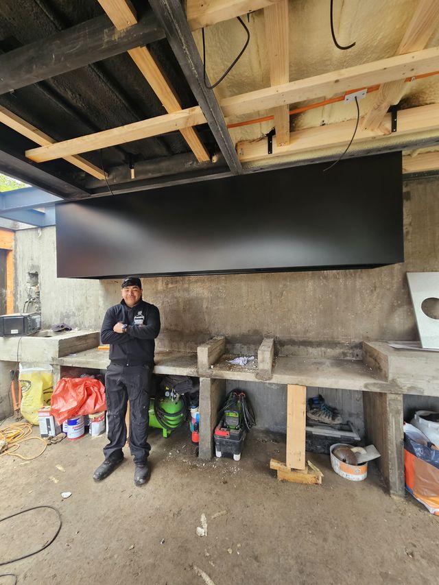 Campana rectangular colgante en un quincho en obra, con instalador