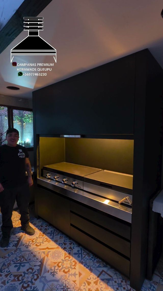 Campana con puerta guillotina integrada en muebles negros, con la parrilla iluminada
