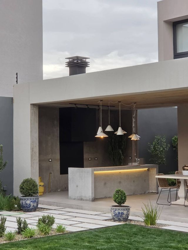 Quincho exterior de una casa moderna en Lo Barnechea, con isla de hormigón y lámparas colgantes