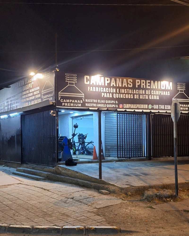 Fachada iluminada del taller de Campanas Premium, de noche