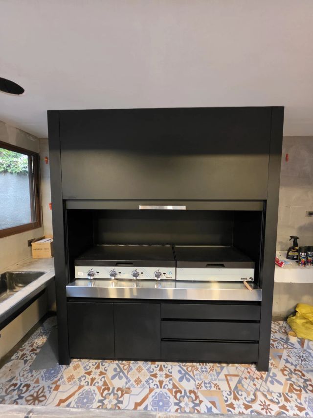 Quincho modular negro con parrillas de acero, a la luz del día