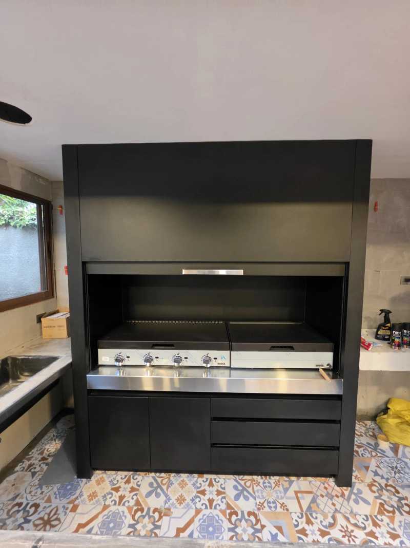 Quincho modular negro con parrillas de acero, a la luz del día