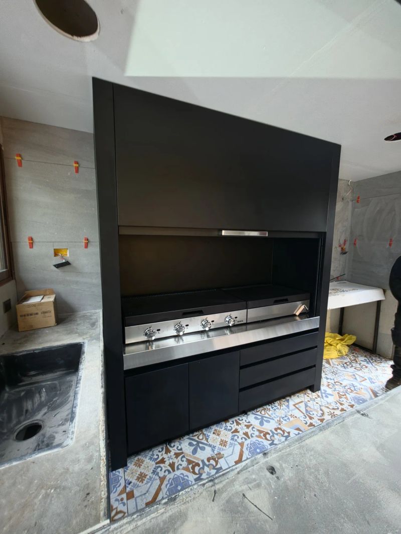 Quincho modular con la puerta guillotina abierta, dejando a la vista las parrillas