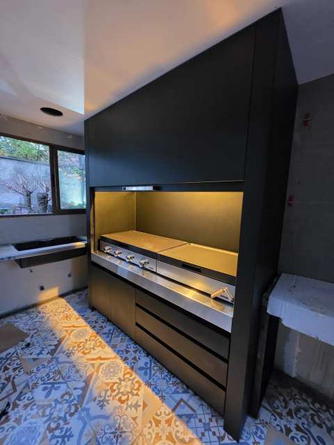 Quincho modular negro con puerta guillotina e iluminación interior