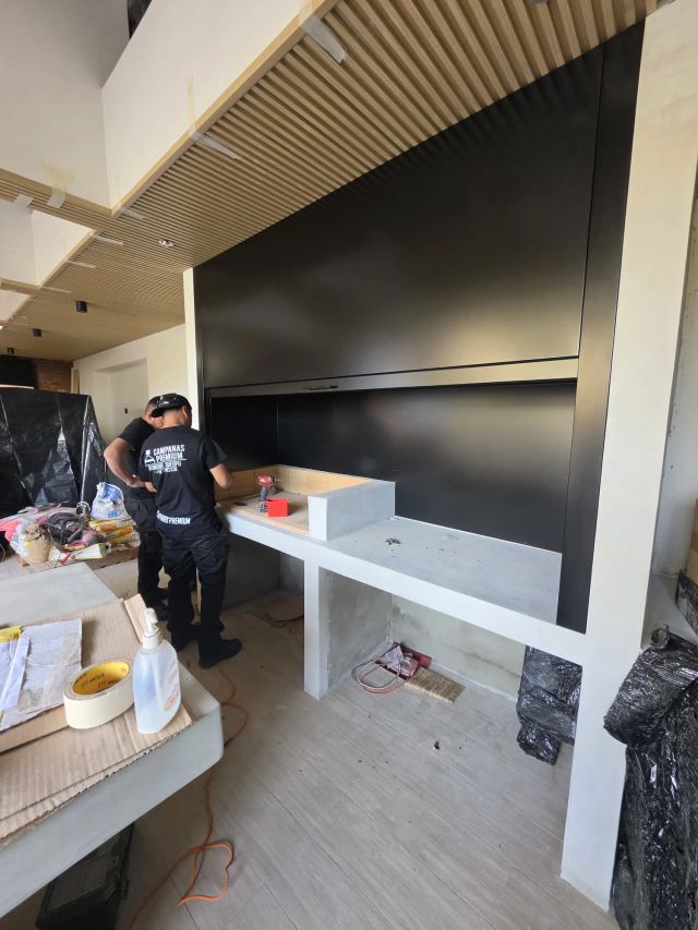 Instaladores montando un mueble negro en un quincho en obra